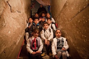 Children pose for a group portrait in the hallway of a house shared by four families.  UNICEF