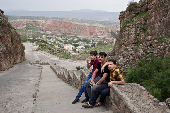 Three young men from Anbar province sit on a wall that overlooks the town of Shaqlawa.