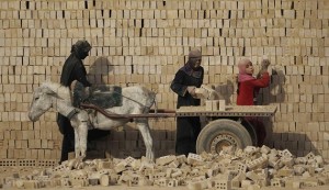 Female workers load bricks on a donkey driven cart in a brick factory in the town of Nahrawan east of Baghdad