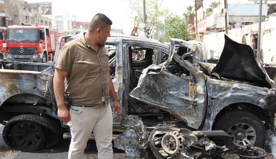 A member of the Iraq security forces looks at the site of a car bomb attack in Baghdad